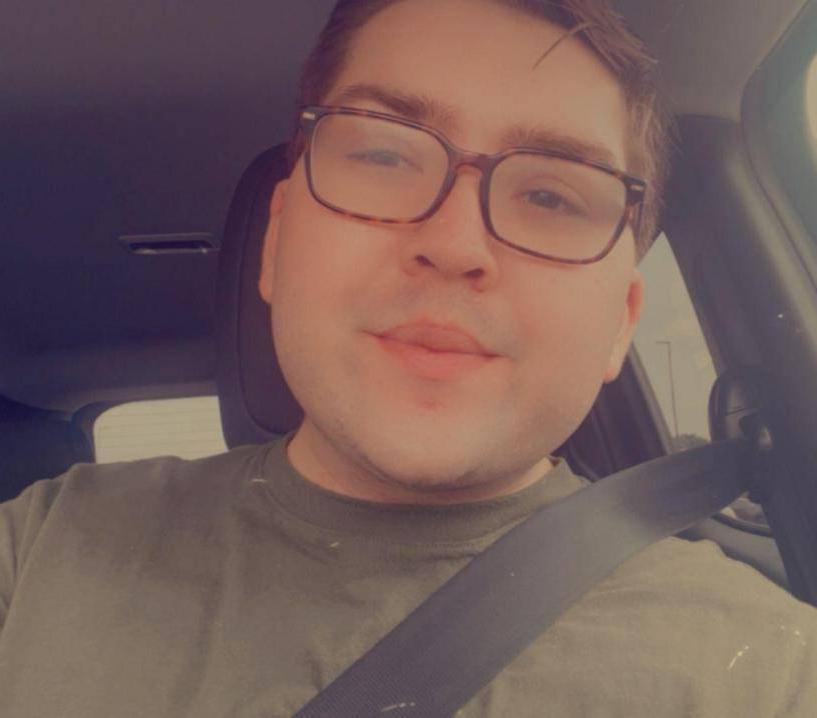 Boy sitting in car with seat belt, smiling at camera